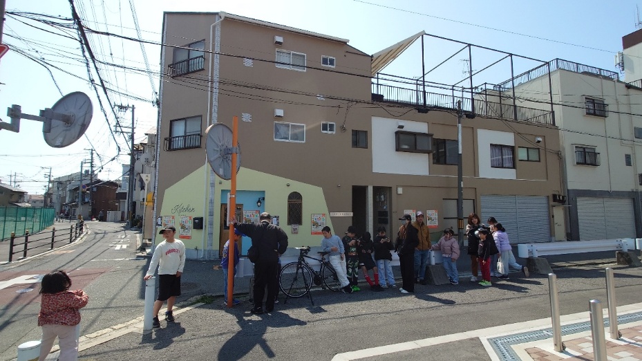 子ども食堂の行列に並ぶ親子連れ